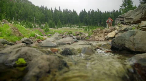 Mountain stream with hikers in the distance Stock Footage 59574591