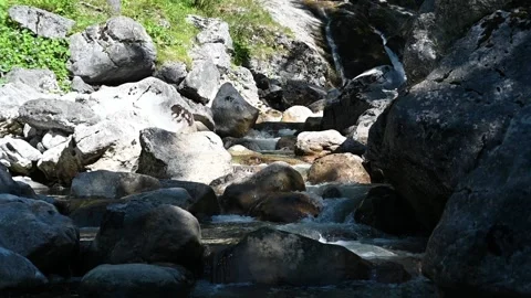 A mountain stream with rocks and a waterfall in the background (slow motion) Stock-Footage 219388576