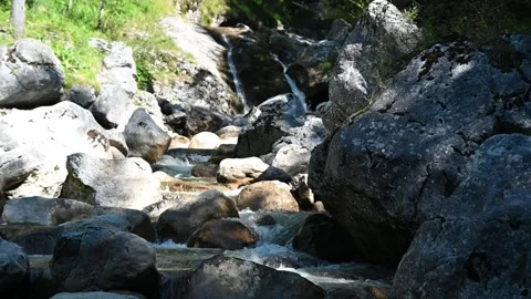 A mountain stream with rocks and a waterfall in the background (slow motion) Stock-Footage 219418707