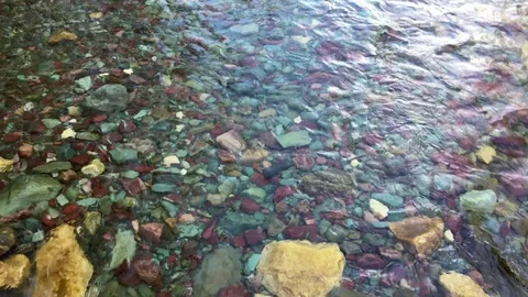 Mountain stream running gently over colored river rocks Stock Footage 78241964