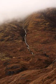 Mountain stream running from its source into glen in Scottish Highlands Stock Photos