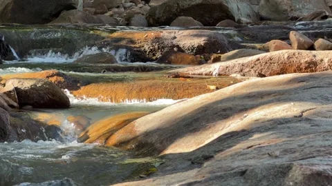 Mountain stream runs across rocks in slow motion, highlighting calm water 库存影片 329276759