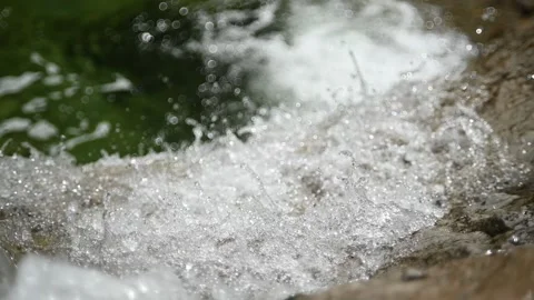 A mountain stream runs over rocks into a pool in summer (slow motion, bokeh) Stock-Footage 219636056