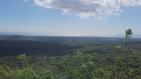 Mountain summit view over green plains and sea with radiant sun flare 4K Stock Footage 329073975