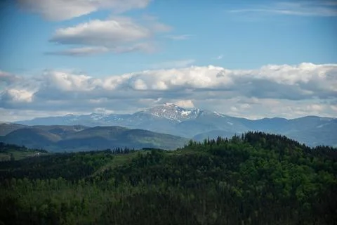 Mountain summit view under a cloudy sky in a lush landscape with green forests Stock Photos