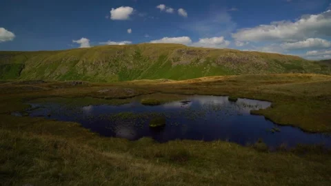 Mountain tarn and white fluffy clouds Stock Footage 346920981