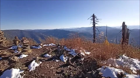 Mountain top with stone pyramids covered with snow, dry grass Stock Footage 290474764