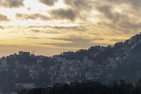 Mountain town skyline under cloudy sunset sky with misty hills and resident.. 写真素材