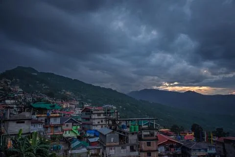 Mountain Town Under Dramatic Cloudy Sky During Twilight Stock Photos