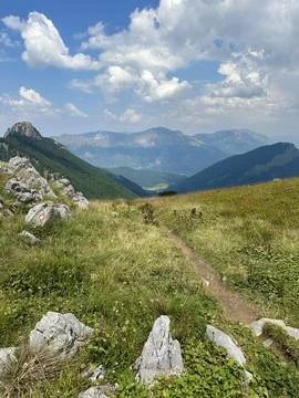 Mountain trail cutting through grass and rocks with a stunning view Stock Photos