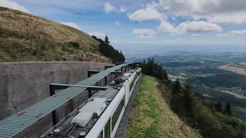 Mountain train climbing Puy de Dome with paragliders in sky, France Stock Footage 346867414