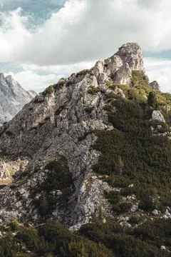 A mountain with trees and rocks under a cloudy sky Stock Photos