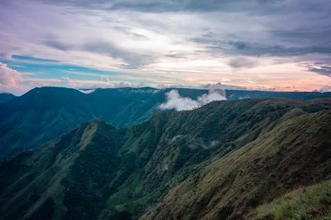 Mountain valley with dramatic sunset sky and low clouds at evening Фото