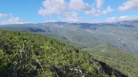 Mountain valley landscape framed by trees with blue sky and clouds 4k Vidéo 329074608