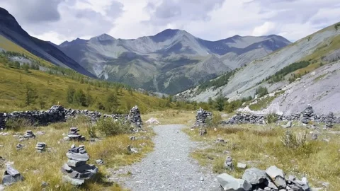 Mountain valley path lined with stacked stones, alpine landscape Vidéo 348190411
