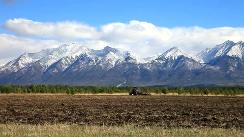 Mountain valley in spring. Tractor working on the field Stock Footage 87640256