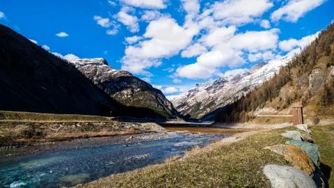 Mountain valley with stream, trees, small hut and dried Livigno lake, Alps Stock-Fotos