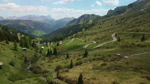 Mountain valley with winding alpine road and distant peaks Vidéo 337079124