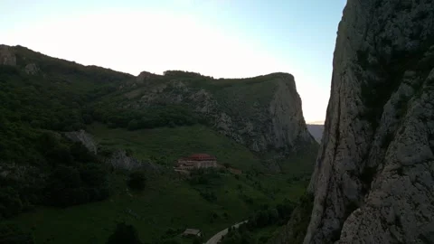 Mountain valley with winding road and building at sunset Stock Footage 345165947