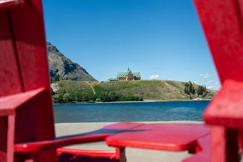 Mountain view from between two red chairs at lakeshore during daytime. Stock Photos