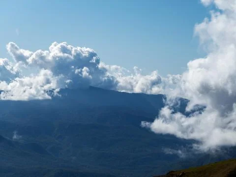 Mountain view with clouds lying on the mountains and clear blue sky Stock Photos
