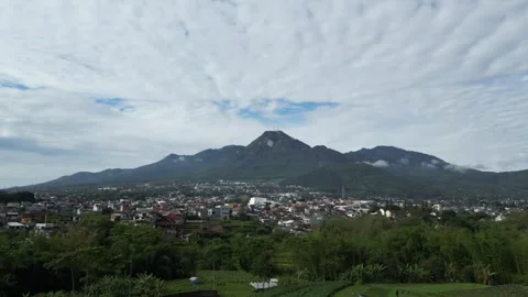 Mountain view with cloudy blue sky and residential buildings and fields Stock Footage 318111367