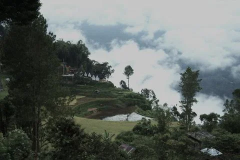 A mountain view with a cloudy sky and a small pond Stock Photos
