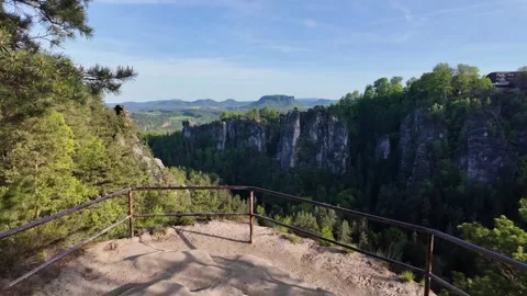 Mountain viewpoint with metal railing overlooking forested valley and dramatic Stock Footage 319475020