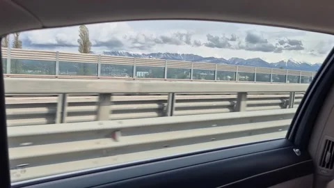 Mountain views flash past the car window as you drive along the highway Video stock 309675021