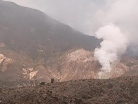 A mountain with a volcano on top and a cloud of smoke rising from it Foto stock