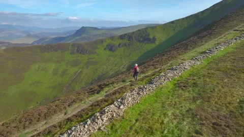 Mountain walker stopped on path overlooking deep green valley. Camera Stock Footage 276739676