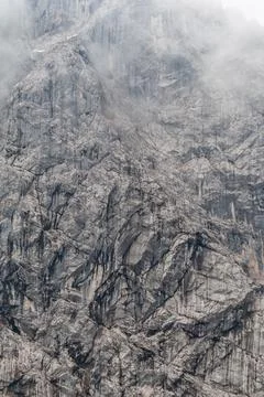 Mountain wall - texture of a rock wall in the mountains with clouds Stock Photos