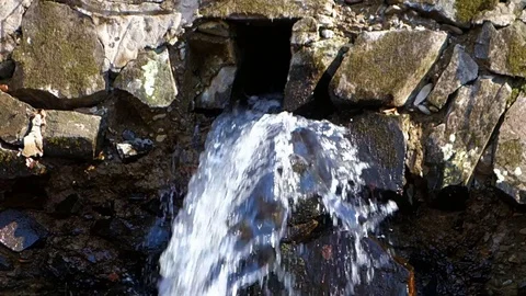 Mountain water flows from a stone dam Stock Footage 128235940