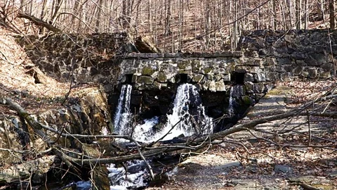 Mountain water flows from a stone dam Stock Footage 128236264