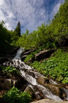 Mountain waterfall on the background of the sky with a summer sunny day. Stock Photos