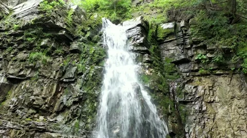 Mountain waterfall bottom view with a green forest on the top, aerial view Stock Footage 236354320