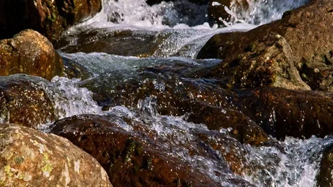 Mountain waterfall cascading over sunlit rocks. Stock Footage 118386411