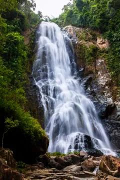 Mountain waterfall falling on the rocks. Dark background. Stock Photos