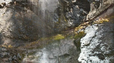 Mountain waterfall rains down on mossy rock Stock Footage 112920