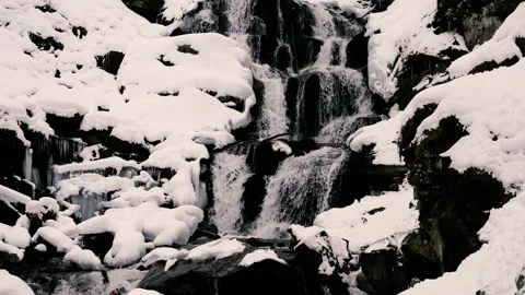 Mountain waterfall. A small waterfall flows through the snow. Video stock 154332957