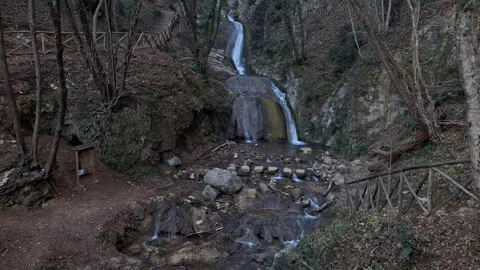 Mountain waterfalls surrounded by a lush forest, a hiking path and rocks Stock Footage 296500722