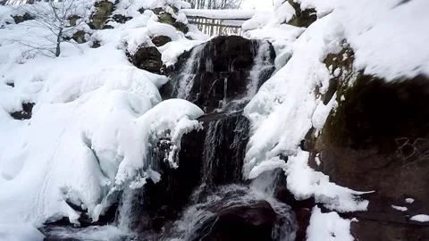 Mountain winter waterfall. water falls from the mountains through the snow Video stock 223570675