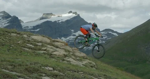 Mountainbiker jumps over rocks riding in high mountain range. Stock Footage
