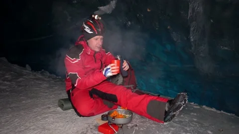 A mountaineer caver eats in a deep ice cave Video stock 234272549
