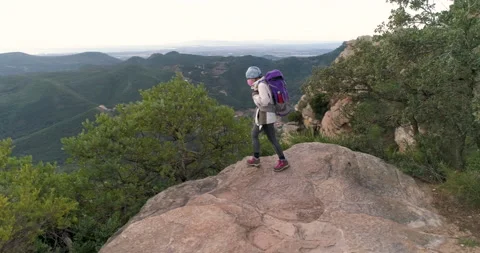 Mountaineer on the edge of the precipice with backpack and coronavirus mask 스톡 동영상 147955541
