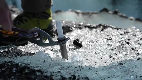 Mountaineer inserting an ice screw into the ice to secure a climbing rope Stock Footage 282247867