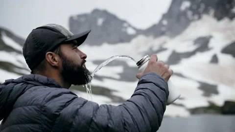 Mountaineer man high in the mountains drinking clean cold water Stock Footage 138690872
