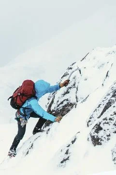 Mountaineer using an ice axe to climb Forcan Ridge in Glen Shiel, Scotland Stock Photos
