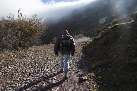 Mountaineer walks down a dirt track, Pyrenees, Spain Stock Photos