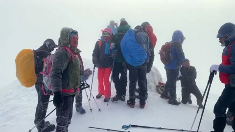 Mountaineers standing front view on Mount Ararat summit in storm wind Stock Footage 343804991